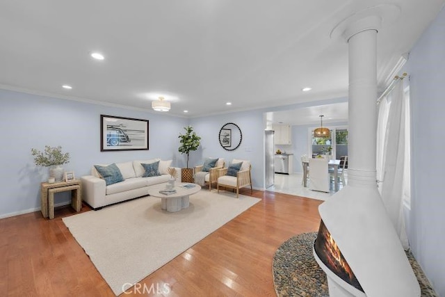 living room featuring ornamental molding, wood finished floors, and decorative columns