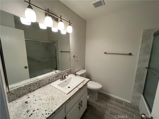 full bath with wood finish floors, shower / bath combination with glass door, visible vents, toilet, and vanity