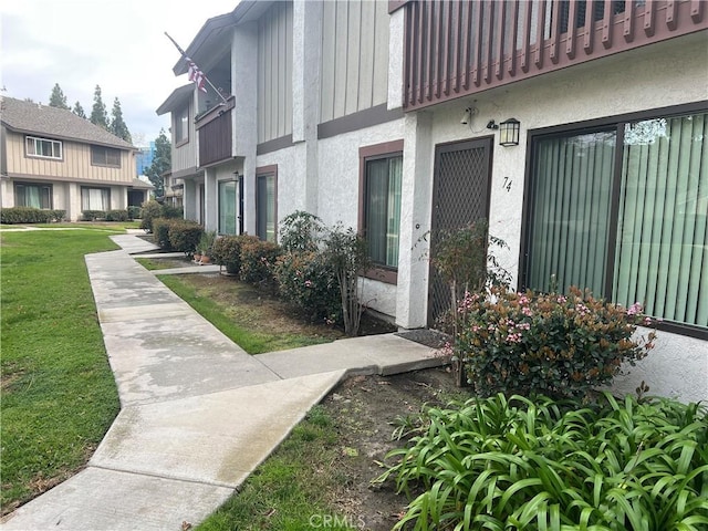 view of exterior entry featuring a lawn and stucco siding