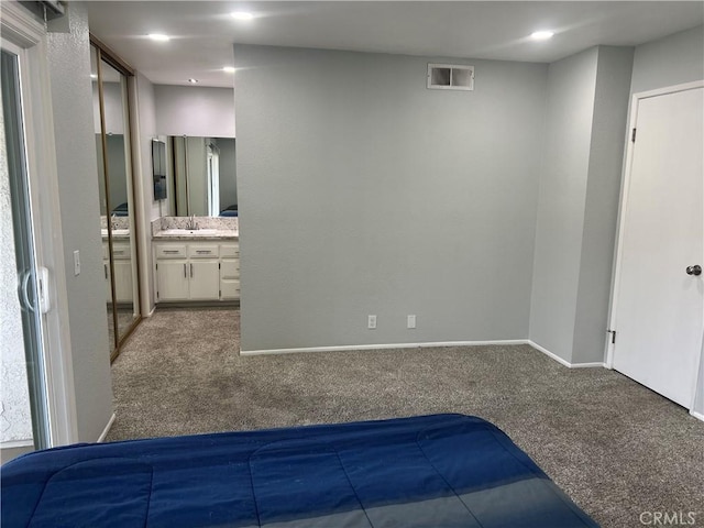 unfurnished bedroom with baseboards, visible vents, connected bathroom, carpet floors, and a sink