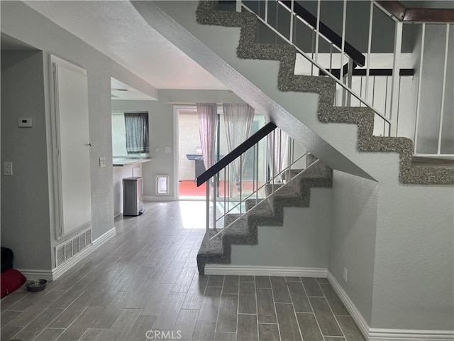 stairway featuring baseboards, visible vents, and wood finish floors