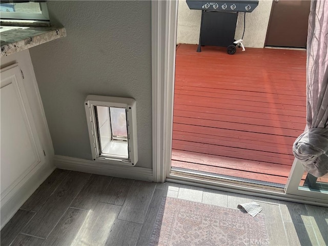 interior space featuring a textured wall, baseboards, and wood finished floors