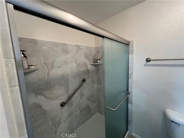 full bath featuring toilet, a stall shower, and a textured wall