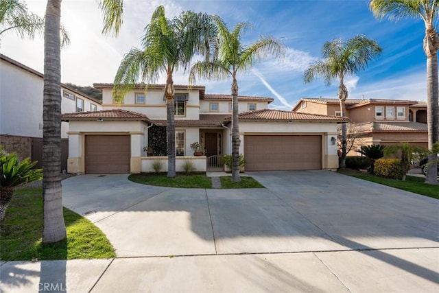 mediterranean / spanish house featuring a tiled roof, an attached garage, driveway, and stucco siding