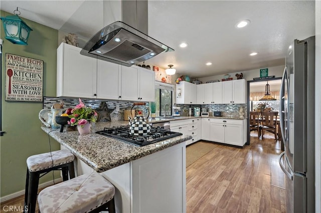 30451 San Pasqual Rd, Temecula, CA 92591 - kitchen featuring freestanding refrigerator, island exhaust hood, gas stovetop, a peninsula, and light wood-style flooring