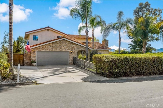 mediterranean / spanish home featuring concrete driveway, an attached garage, fence, and a tile roof