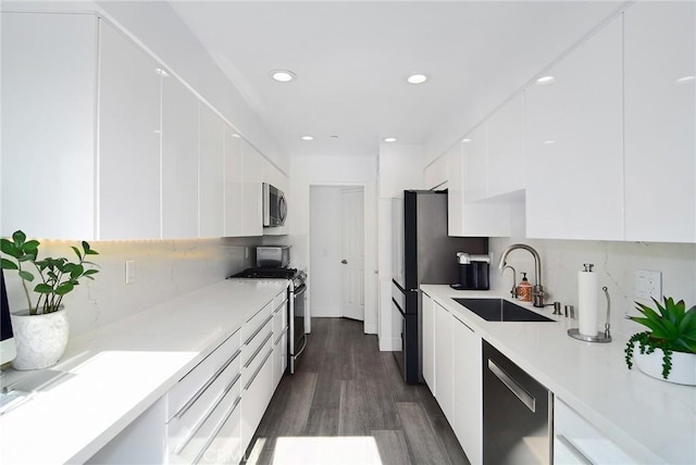 kitchen featuring appliances with stainless steel finishes, white cabinets, decorative backsplash, sink, and dark hardwood / wood-style floors