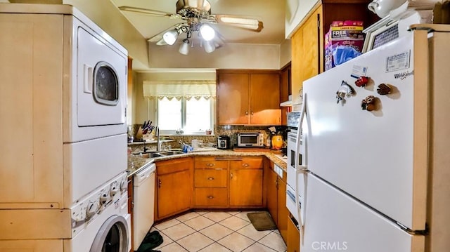 kitchen featuring white appliances, brown cabinets, a sink, and stacked washer and clothes dryer