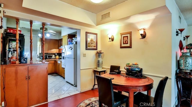 kitchen featuring ceiling fan, light tile patterned floors, a peninsula, visible vents, and freestanding refrigerator