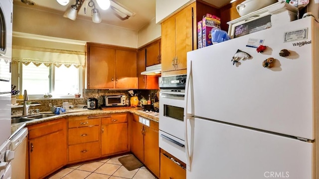 kitchen with white appliances, tasteful backsplash, brown cabinetry, a sink, and a warming drawer