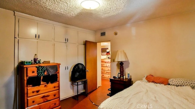 bedroom with visible vents, dark wood-style flooring, and a textured ceiling