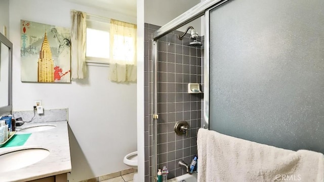 full bathroom with double vanity, toilet, a sink, a shower stall, and tile patterned flooring