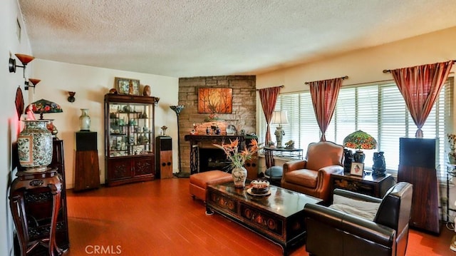 sitting room featuring a textured ceiling, wood finished floors, and a stone fireplace