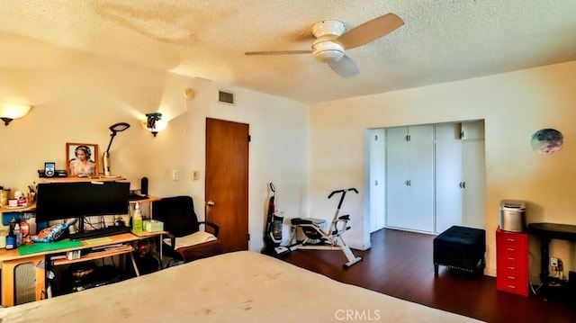 bedroom with visible vents, dark wood finished floors, a ceiling fan, a textured ceiling, and a closet