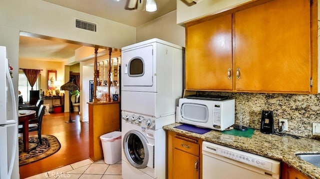 clothes washing area featuring laundry area, light tile patterned floors, visible vents, stacked washer and clothes dryer, and ceiling fan