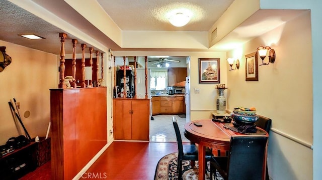 dining area with a ceiling fan, visible vents, a textured ceiling, and wood finished floors