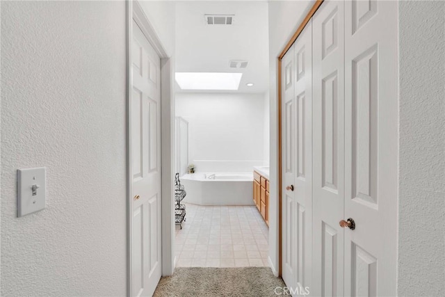 hallway with light tile patterned floors and a skylight