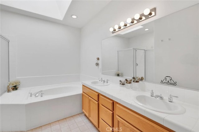 bathroom featuring a skylight, independent shower and bath, and vanity