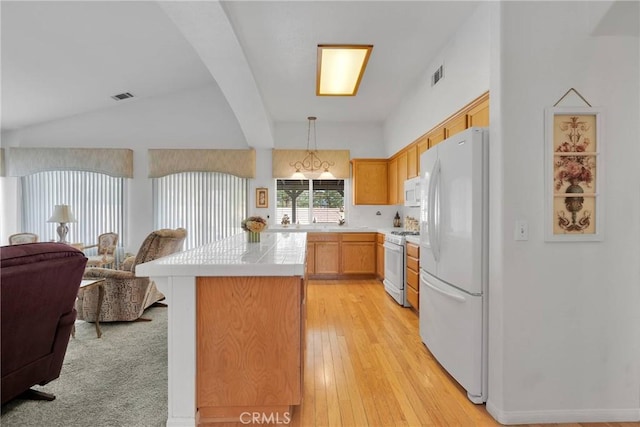 kitchen featuring white appliances, light wood-type flooring, a center island, decorative light fixtures, and light brown cabinets