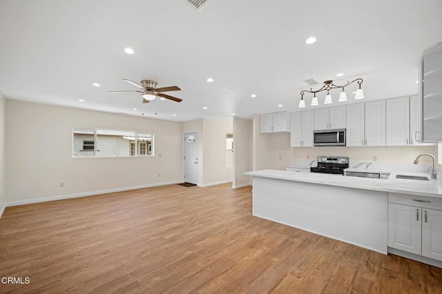 kitchen with stainless steel appliances, light hardwood / wood-style floors, sink, light stone counters, and white cabinets