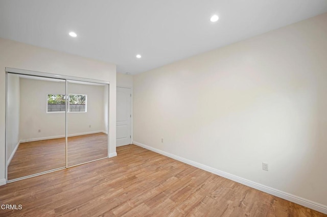 unfurnished bedroom with light wood-type flooring and a closet