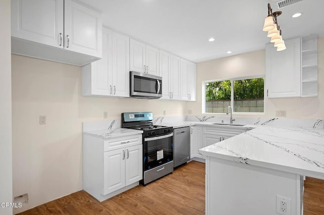 kitchen featuring kitchen peninsula, stainless steel appliances, light hardwood / wood-style flooring, sink, and white cabinets