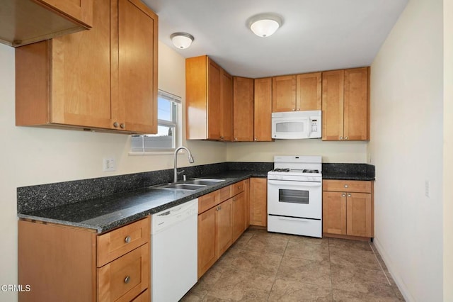 kitchen with white appliances, dark stone countertops, and sink