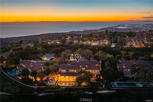 aerial view at dusk featuring a water view