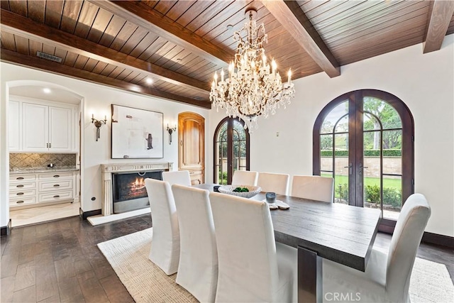 dining area with a warm lit fireplace, arched walkways, french doors, and a wealth of natural light