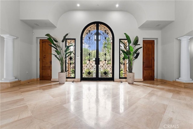 entrance foyer with decorative columns, a high ceiling, and french doors