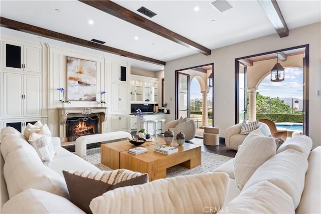 living area with recessed lighting, beam ceiling, visible vents, and a lit fireplace