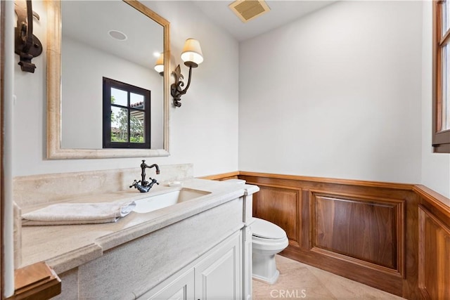 bathroom featuring visible vents, wainscoting, vanity, and toilet