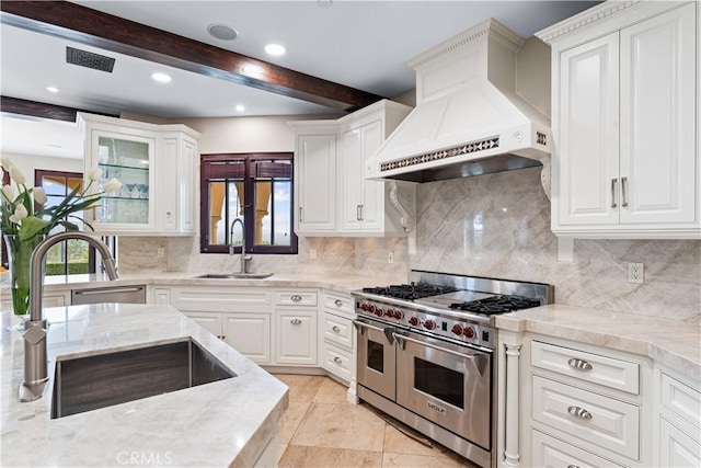 kitchen with custom range hood, beam ceiling, range with two ovens, and a sink