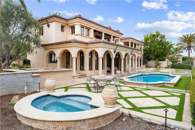 rear view of property featuring a patio area, a tiled roof, a balcony, and stucco siding