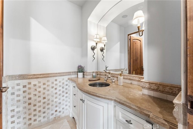 bathroom with tile patterned flooring, vanity, tile walls, and wainscoting