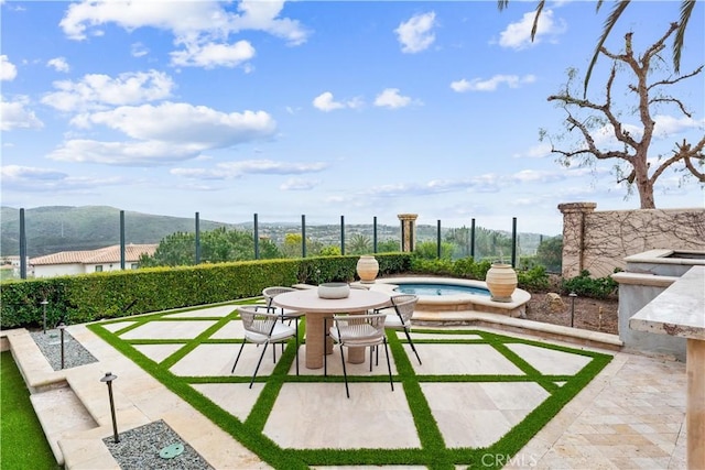 view of patio with fence, a hot tub, and a mountain view