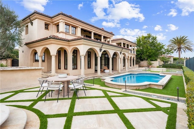 back of house featuring a patio area, fence, a tiled roof, and a balcony