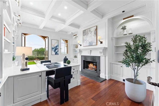 office space with dark wood finished floors, coffered ceiling, a lit fireplace, built in shelves, and beam ceiling