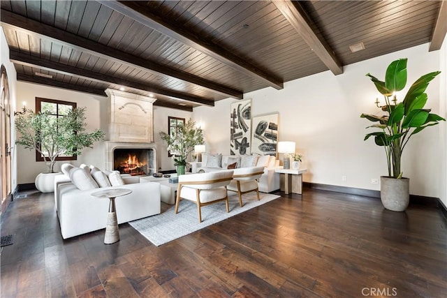 living room featuring a large fireplace, beam ceiling, baseboards, and wood finished floors