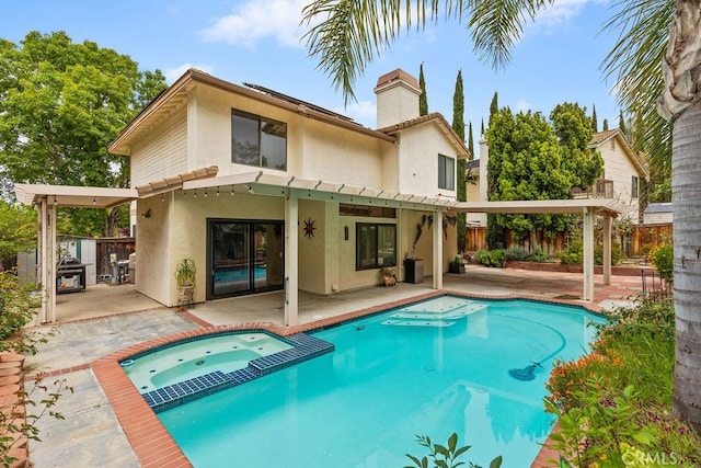 rear view of property with a patio area, stucco siding, fence, and a pool with connected hot tub