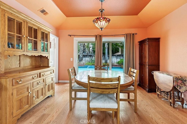 dining area featuring visible vents, light wood-type flooring, and a tray ceiling