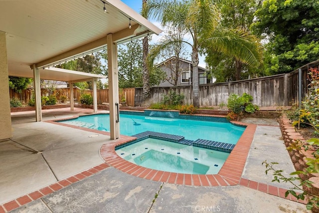 view of pool featuring a patio area, a fenced backyard, and a pool with connected hot tub