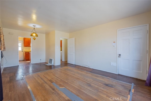 unfurnished living room with dark wood-type flooring and visible vents