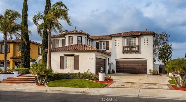 mediterranean / spanish-style house with concrete driveway, an attached garage, a tiled roof, and stucco siding