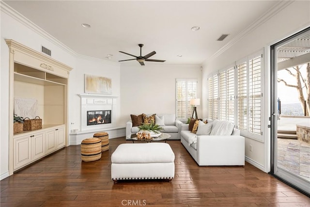 living room featuring dark wood-style floors, visible vents, and ornamental molding