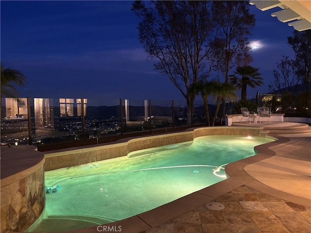 pool at night featuring a patio area and an outdoor pool