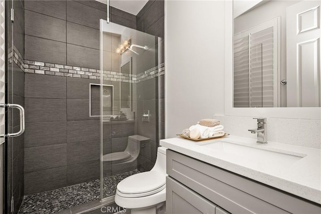 bathroom with toilet, a stall shower, and vanity