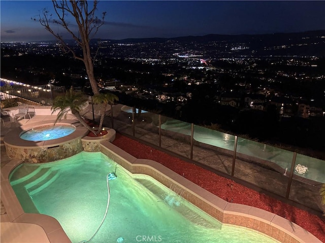 pool at night featuring an outdoor pool and an in ground hot tub