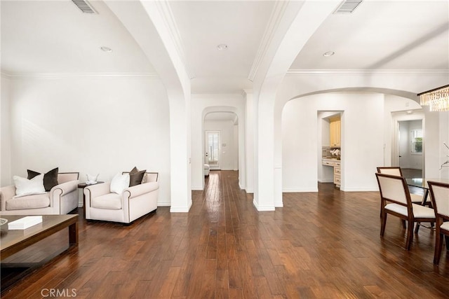 living room featuring dark wood-style floors, visible vents, arched walkways, and ornamental molding