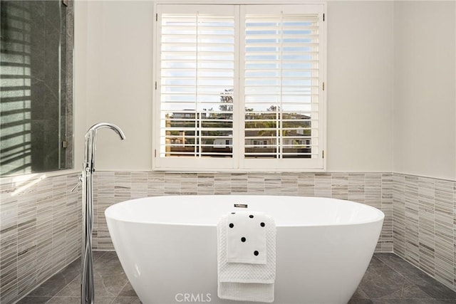 full bathroom with a freestanding bath, a wainscoted wall, tile patterned flooring, and tile walls